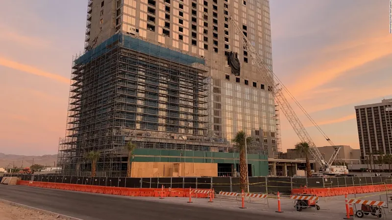 A tall building under construction with extensive scaffolding and a crane on the right.